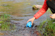 © Antonioguillem - Hiker filling canteen with river raw water