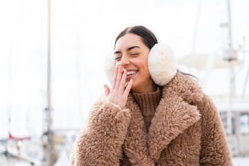 Wall Mural - Young woman wearing winter muffs at outdoors smiling a lot