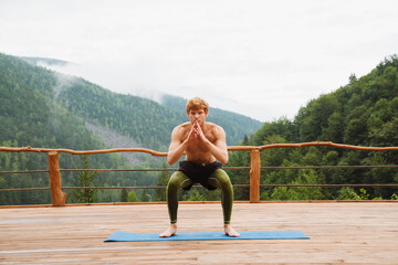 Wall Mural - Young white man practicing yoga while doing workout in forest