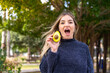 Young pretty Romanian woman holding an avocado at outdoors with surprise and shocked facial expression