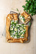 Zucchini and cheese phyllo dough tart with green peas, micro greens and basil. Zucchini and feta pizza, filo puff pastry. Savoury vegetable vegetarian baking.