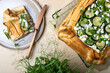 Zucchini and cheese phyllo dough tart with green peas, micro greens and basil. Zucchini and feta pizza, filo puff pastry. Savoury vegetable vegetarian baking.