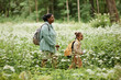 © Seventyfour - Side view portrait of mother and daughter walking across meadow while hiking in nature together