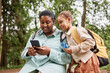 © Seventyfour - Portrait of happy mother and daughter hiking together and using smartphone app