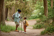 © Seventyfour - Side view portrait of black mother and daughter hiking together standing in beautiful forest trail, copy space
