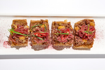 Canvas Print - Aesthetic composition with shredded beef bruschetta on white background over white wall. Italian bruschetta with shredded beef and mustard on fine dining in summer. Elegant menu concept.