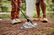 © Seventyfour - Close up of child picking up plastic bottle outdoors in nature, copy space