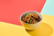 Asian fried buckwheat noodles with chicken on coloured background Fried noodles in ceramic bowl on yellow, red and blue background. Stir-fry soba in trendy style with shadows. Vibrant food