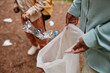 © Seventyfour - High angle close up of mother and daughter helping clean nature and putting plastic bottle in trash bag outdoors