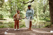 © Seventyfour - Full length portrait of black mother and daughter helping clean nature and picking plastic bottles in forest