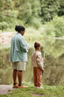 © Seventyfour - Vertical back view portrait of mother and daughter fishing together by river and enjoying nature