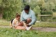 © Seventyfour - Portrait of caring black mother putting band aid on knee of little girl injured during nature hike, copy space