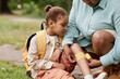 © Seventyfour - Portrait of black little girl injured in nature hike with mother putting bandage on knee outdoors