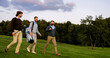 © ihorvsn - Handsome male friends walking with their clubs on the golf pitch to play a game, talking and laughing.