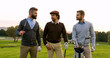 © ihorvsn - Portrait of three golf players looking at each other and posing to the camera with clubs on a sunny day. Outdoors
