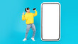 Asian Teen Guy Near Huge Phone Singing On Blue Background