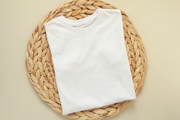 white folded t-shirt mockup on wicker table mat, front of blank shirt, space for design presentation