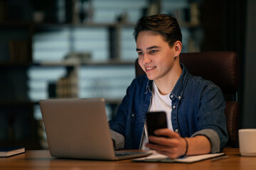 Aufkleber - Cheerful guy employee working at office, using laptop and smartphone