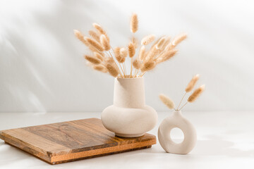 vase set with dried lagurus grass on wooden podium with copy space on the table with shadows. wooden