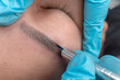 © Mdv Edwards - An esthetician using a microblade tool to make small cuts into the eyebrow of a customer. A Microblading technique to implant pigment.