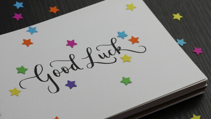 Wall Mural - GOOD LUCK lettering in notebook with colorful stars on black wooden desk