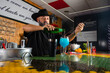 © Rafa - hombre barman con gorro de vaquero preparando un cóctel azul en la barra del bar