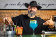 © Rafa - hombre barman con gorro de vaquero preparando un cóctel azul en la barra del bar