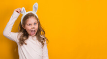 Little Funny Girl With Easter Bunny Ears On Yellow Background With Copy Space.