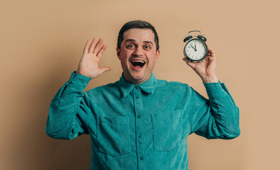 Wall Mural - surprised caucasian man in green shirt with vintage alarm clock on brown background