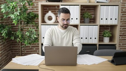 Sticker - Young hispanic man business worker using laptop throwing documents at office