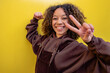 © VISTA by Westend61 - Smiling woman with curly hair gesturing peace sign