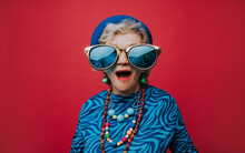 Surprised Senior Woman Wearing Big Sunglasses Against Red Background