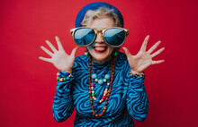 Senior Woman Wearing Big Sunglasses Having Fun Against Red Background