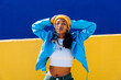 © VISTA by Westend61 - Confident young woman wearing blue jacket standing in front of yellow wall