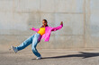 © VISTA by Westend61 - Smiling young woman dancing in front of wall