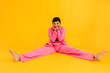 © VISTA by Westend61 - Happy young woman sitting with legs apart in over yellow background
