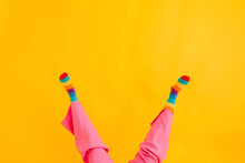 Feet Of Woman Wearing Multi Colored Socks Against Yellow Background