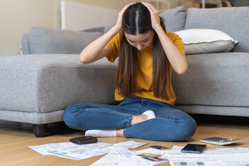 Wall Mural - Financial owe asian woman sitting face expression stressed by calculate expense from invoice or bill sitting on floor at home, have no money to pay, mortgage or loan. Debt, bankruptcy or bankrupt.