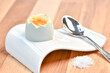 a single boiled egg in an egg cup broken open showing yolk with a spoon on a wooden surface