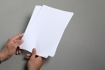 Wall Mural - man holding sheets of paper on grey background, closeup. mockup for design