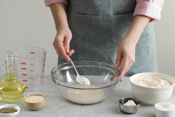 Woman making dough for traditional grissini at light grey marble table indoors, closeup