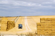 Two stacks of haybales with tractor in field