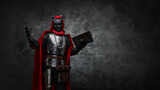 Fototapeta Przestrzenne - Shot of mysterious cultist dressed in steel armor and red mantle holding book.