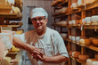 © .shock - A worker at a cheese factory sorting freshly processed cheese on drying shelves