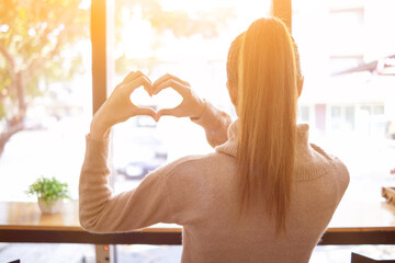 blurred background Young woman shows her hands up to form heart symbol to show friendship love and kindness because heart is symbol of love. Young woman showing love with heart symbol from her hand