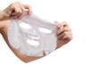 © LeviaUA - Female hands holding sheet of white mask on transparent background