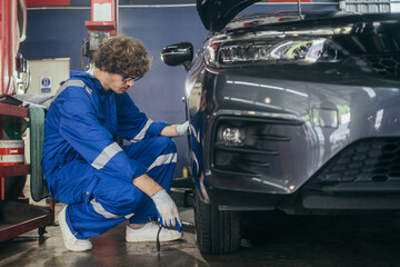 Wall Mural - Automotive mechanic worker checking at car tyre rubber condition needed for replacement. after service at auto repair shop concept