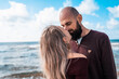 © algrigo - A couple in love on the beach or ocean. Photo against the background of water and the horizon. Young family on a walk along the sandy coast on a pleasant sunny day. Relations between a man and a woman