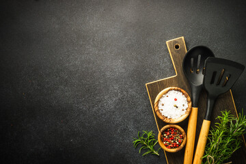 Wall Mural - Food background on black. Kitchen utensils, wooden cutting board and spices. Flat lay with copy space.