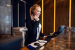 © Dusan Petkovic - A happy receptionist is answering guest's call from a hotel in reception.